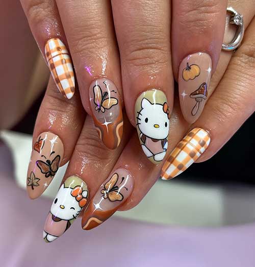 Autumn-themed Hello Kitty nails featuring plaid designs, swirls, pumpkins, mushrooms, and butterflies in warm colors.