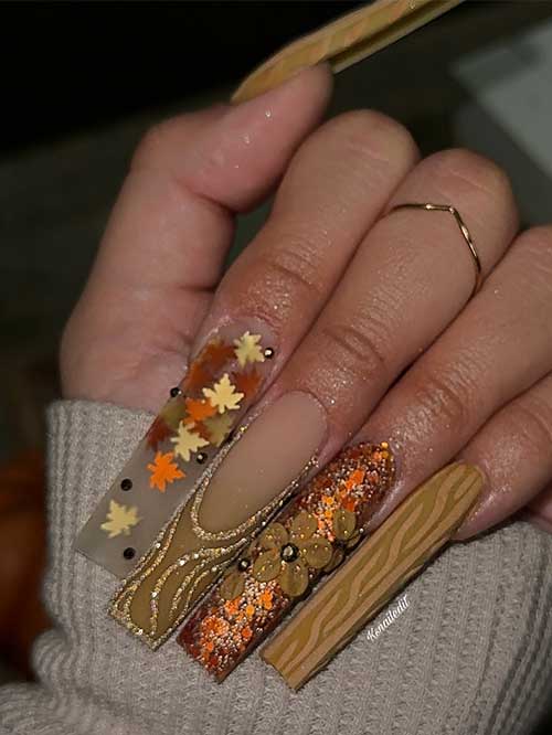 Earthy brown fall nails featuring sweater art, sparkling maple leaves, and carrot cake glitter for a stylish autumn look.