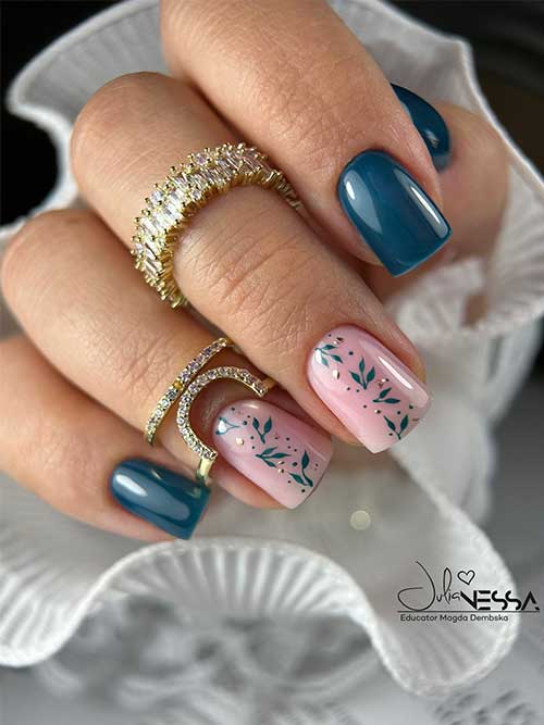 Short glossy Prussian blue nails with two nude pink accents featuring blue leaves and metallic gold dots for added elegance.