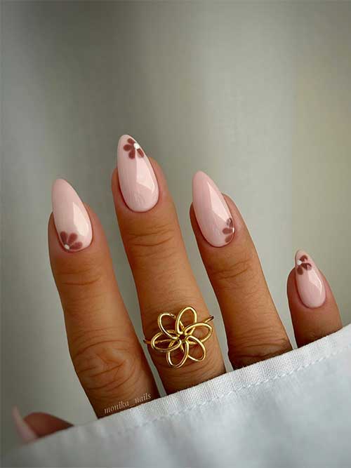 Trendy nude fall nails featuring a delicate brown flower design on each nail, perfect for a stylish autumn look.