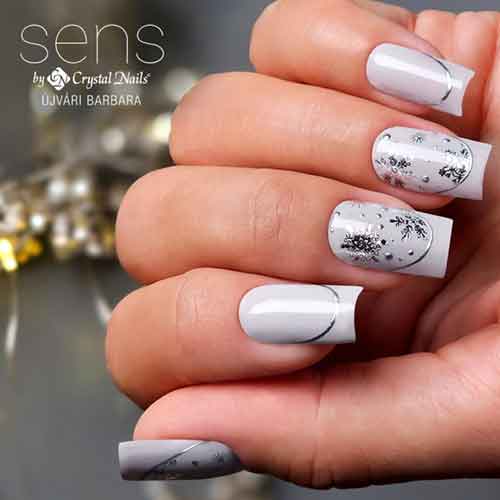 Light gray nails featuring artistic silver chrome French tips adorned with delicate snowflake designs.