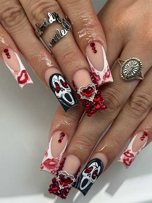 Halloween-themed white French tip nails featuring bloody kisses, a scary face accent, and red gem accents.