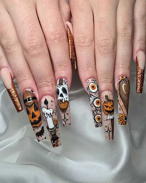 Long coffin-shaped Halloween nails with a nude base, featuring pumpkins, evil eyes, and two gold metallic French tips.