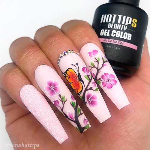 Coffin shaped matte pink nails with blossom and butterfly nail art design which adorned with little silver rhinestones!