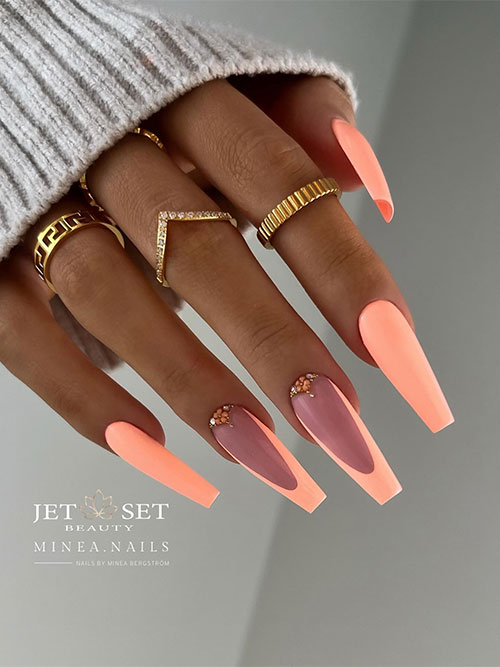 Long coffin neon peach nails with two accent peach French tips adorned with tiny flowers and rhinestones above cuticles