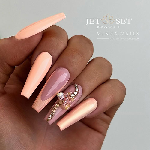 Long peach coffin nails with an accent French tip and a nude accent nail adorned with gold rhinestones and a butterfly