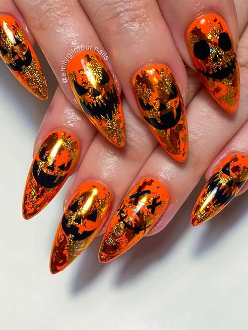 Black Halloween evil pumpkin face nail art over a vibrant burnt orange base color decorated with gold foil patches.