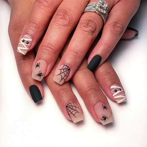 Short matte Halloween press-on nails featuring spider web designs, mummies, and small spiders for a festive look.