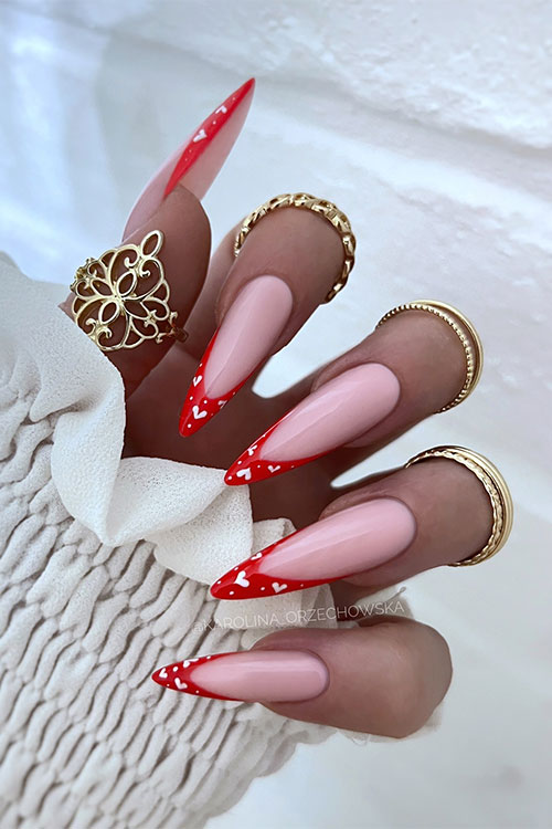 Long glossy stiletto red French manicure with white hearts and dots on the nail tips