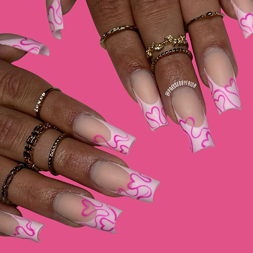 Long light pink French tip nails with hot pink swirls forming heart shapes are one of the best Valentine nail designs to try