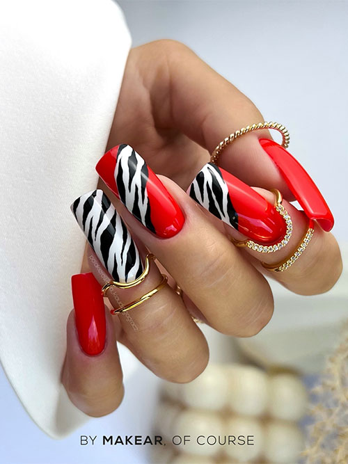 Long glossy red nails with accent black and white zebra prints and two accent red nails adorned with zebra prints