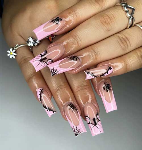 Pastel French pink Halloween nails featuring black cobweb and stitch designs, with a pumpkin accent tip for added flair.