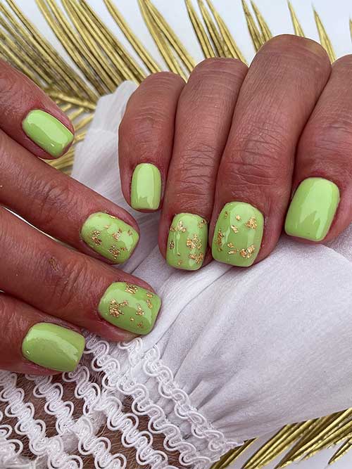 Short crème green nails adorned with gold foil accents, showcasing a vibrant fall aesthetic.