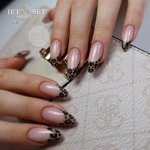 Long almond-shaped leopard French manicure with a nude base color and light brown French tips adorned with leopard prints