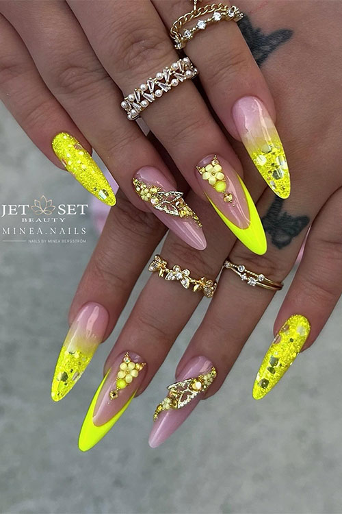 Long almond-shaped neon yellow nails with glitter with a French tip nail adorned with a flower and rhinestones