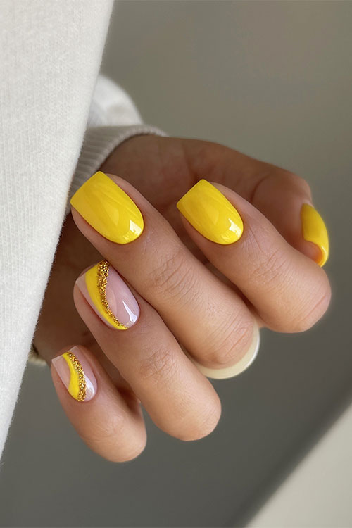 Short yellow summer nails square shaped with two nude accents adorned with yellow and gold glitter negative space swirls