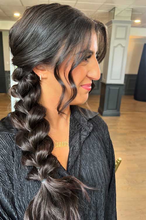 A stylish side braid elegantly draped over one shoulder, showcasing smooth, shiny hair and a polished appearance.