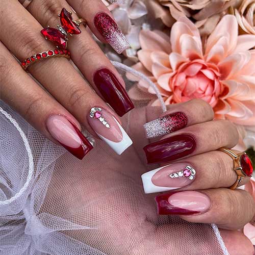 Charming burgundy nail art with a glittery rose gold accent and a white French tip decorated with elegant rhinestones.