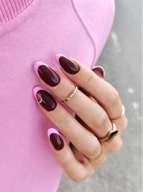 Creative burgundy nails featuring pastel pink French tips and a cherry design on the accent nail.