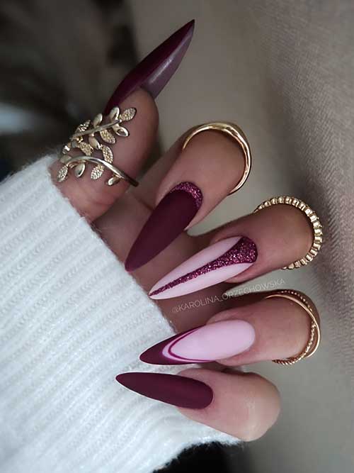 Long stiletto matte burgundy nails with glitter accents and a French tip on a nude pink base.