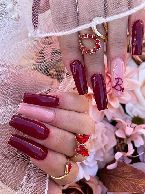 Elegant long burgundy nails complemented by a nude pink accent nail for a chic and sophisticated look.