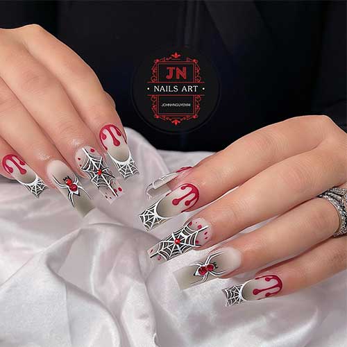 White coffin nails with black ombre, spider web French tips, and accent nails featuring red rhinestone spider designs.