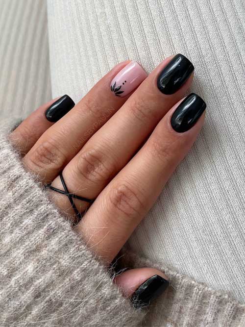 Elegant fall black manicure featuring a black lotus flower on a nude pink accent nail, showcasing a stylish contrast.