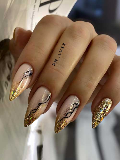 Long almond-shaped winter nails featuring gold glitter and black abstract art on a nude base for 2024.