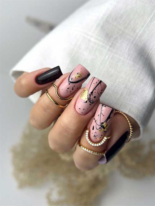 Long black nails featuring three nude accent nails adorned with abstract art and gold foil flakes for a chic look.