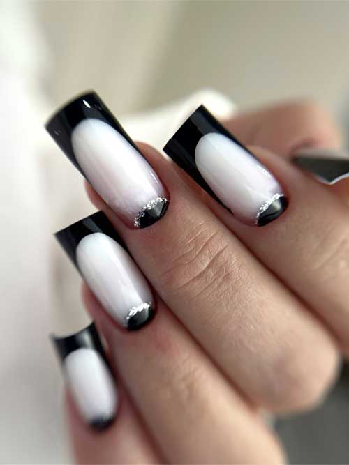 Square-shaped long black French tip nails over a milky white base, embellished with black reverse French art and silver glitter.