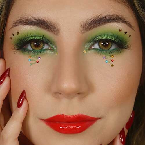 Glittering green Christmas eye makeup paired with glossy red lips, creating a festive and vibrant holiday look.