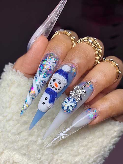 Long stiletto milky white nails adorned with snowflakes, candy cane, and a 3D snowman on an ice blue accent nail.