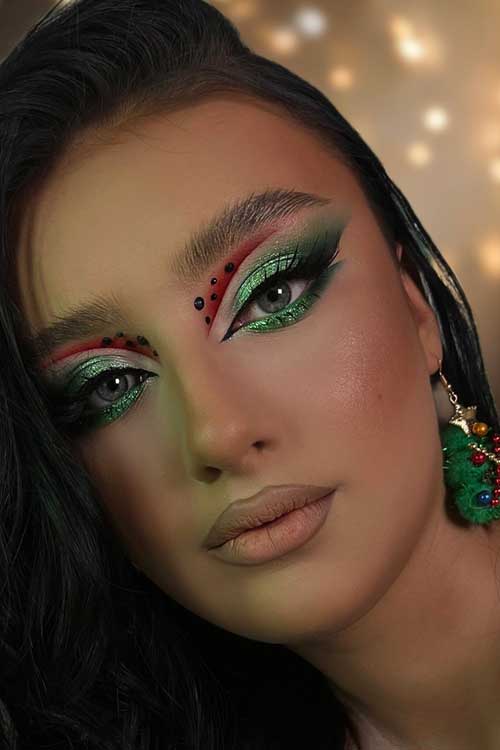 Stunning green glitter Christmas eye makeup paired with matte nude lips, creating a festive and elegant look.